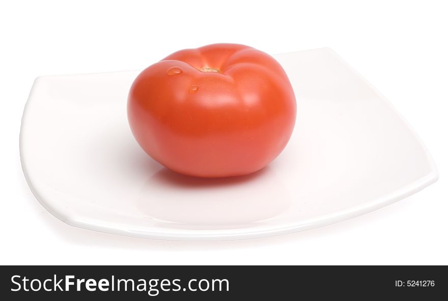 Red ripe tomato lying on a white square ceramic plate. Red ripe tomato lying on a white square ceramic plate