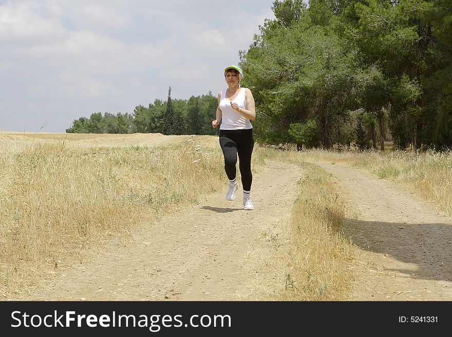 The young woman runs on a path around of a field