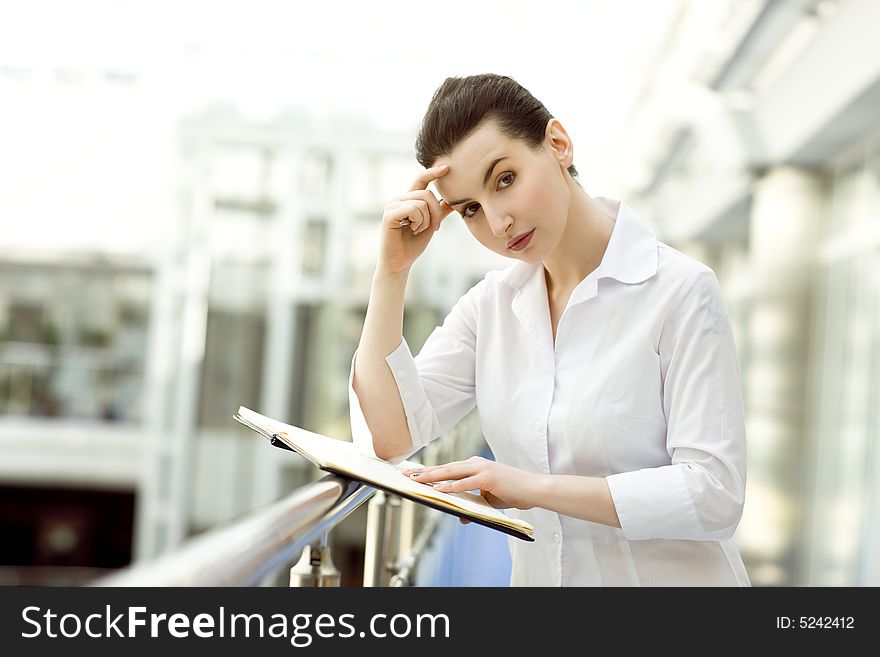 Portrait of young woman standing with business diary in modern office building. Portrait of young woman standing with business diary in modern office building
