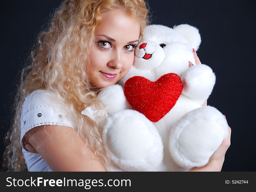 The beautiful girl with a toy in hands on a black background. The beautiful girl with a toy in hands on a black background