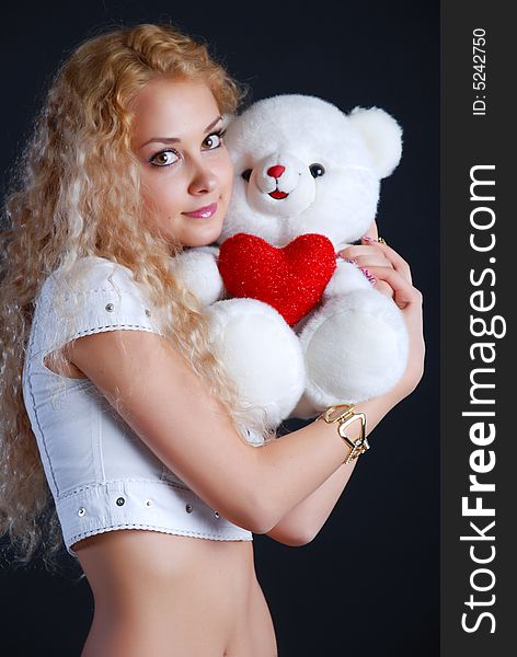 The beautiful girl with a toy in hands on a black background. The beautiful girl with a toy in hands on a black background