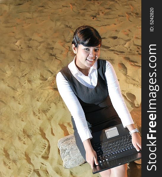 Business woman sitting on peace of wood on the beach's sand