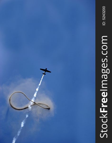 Single engine military stunt plane ascending through smoke ring. Single engine military stunt plane ascending through smoke ring