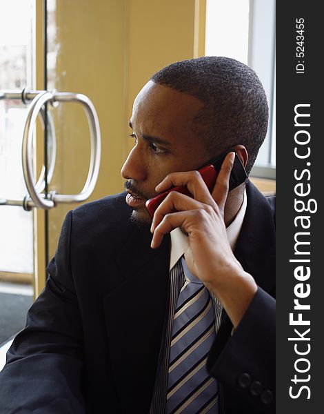 Vertical shot of a businessman, with his head turned away from the camera, in deep thought talking on a cellphone. Vertical shot of a businessman, with his head turned away from the camera, in deep thought talking on a cellphone.