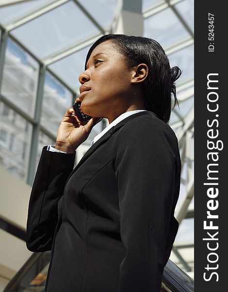 Vertical shot of a businesswoman, talking on a cellphone, standing in an atrium. Vertical shot of a businesswoman, talking on a cellphone, standing in an atrium.