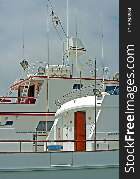 Two white fishing boats moored at a dock showing just the cabins. Two white fishing boats moored at a dock showing just the cabins.