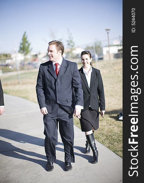 Businesspeople laughing and walking together wearing full suits