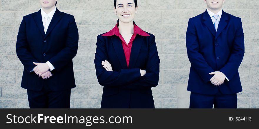 Attractive businesswoman stands between two businessmen in suits. Attractive businesswoman stands between two businessmen in suits