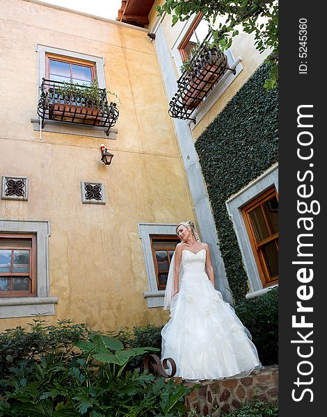 A bride standing in a courtyard in her dress. A bride standing in a courtyard in her dress