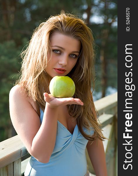 Girl with apple on sunset on green background