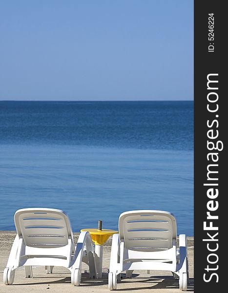 Two plastic chairs at the edge of a sea