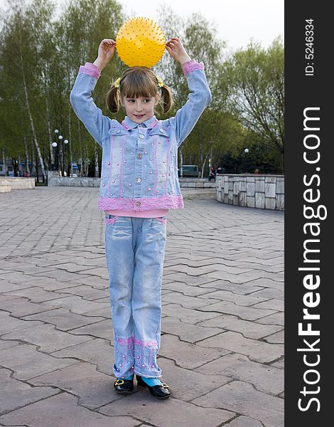 The girl plays with a ball in park and smiles