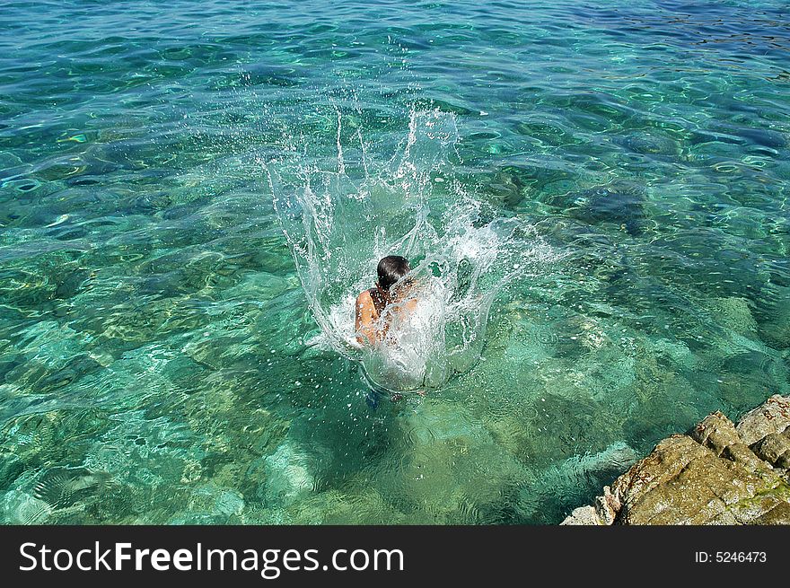 A boy jumping in the limpid sea of Isola d'Elba in Tuscany. A boy jumping in the limpid sea of Isola d'Elba in Tuscany