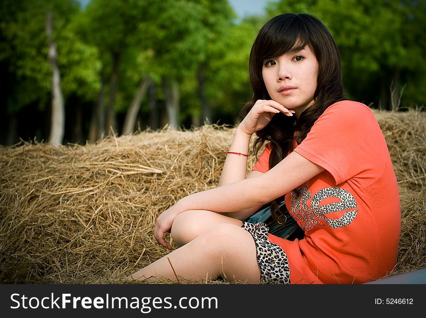 Portrait of young lady sitting on the dried grasses