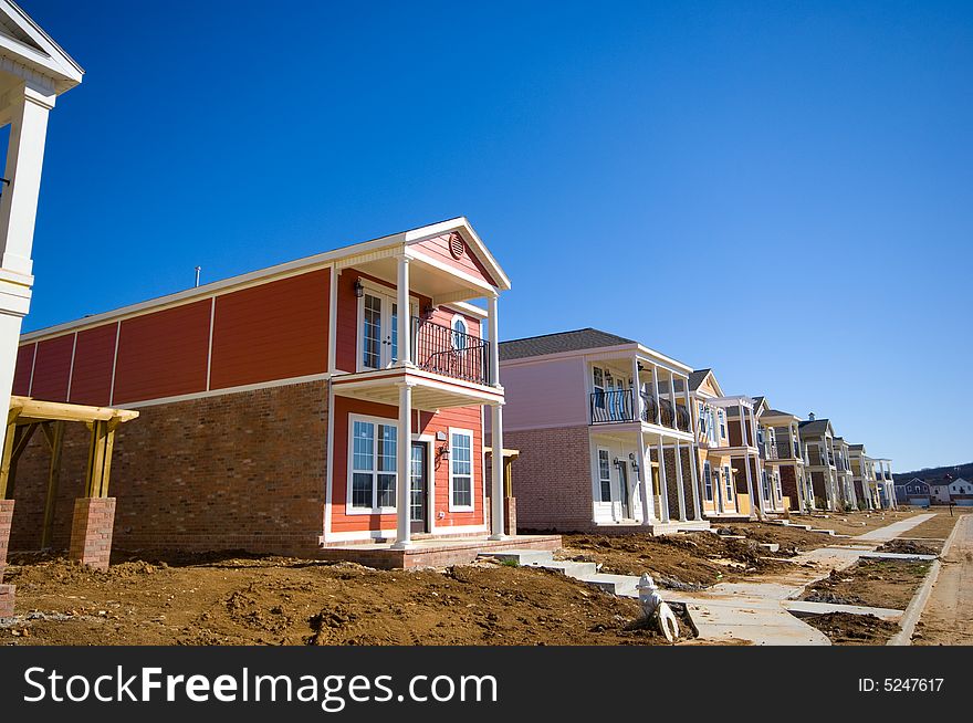 A row of new brightly colored traditional styled homes under construction. A row of new brightly colored traditional styled homes under construction