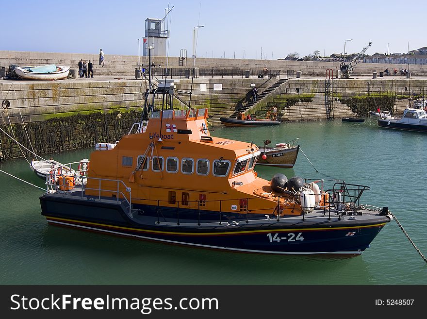 A large lifeboat that is docked in harbour. A large lifeboat that is docked in harbour