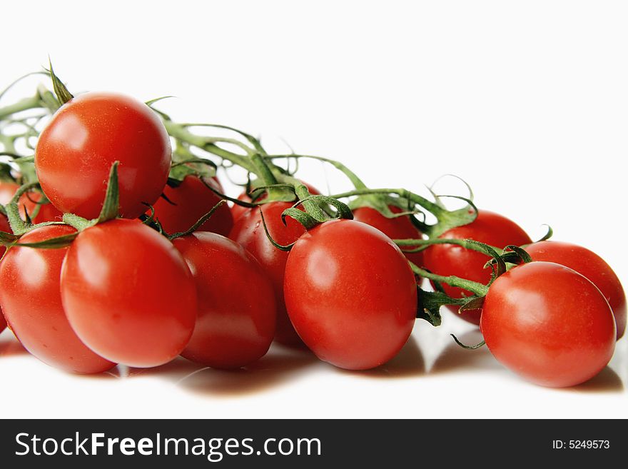 Red cherry tomatoes with a branch on a  light background