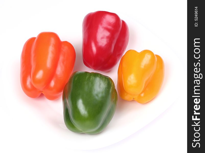 Four colorful peppers on white plate