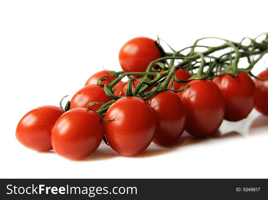 Red cherry tomatoes with a branch on a  light background