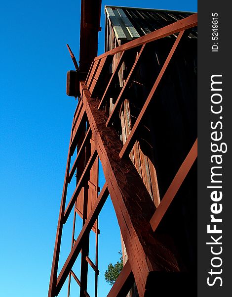 A photograph taken in Sweden of a red wooden windmill sail against a blue sky