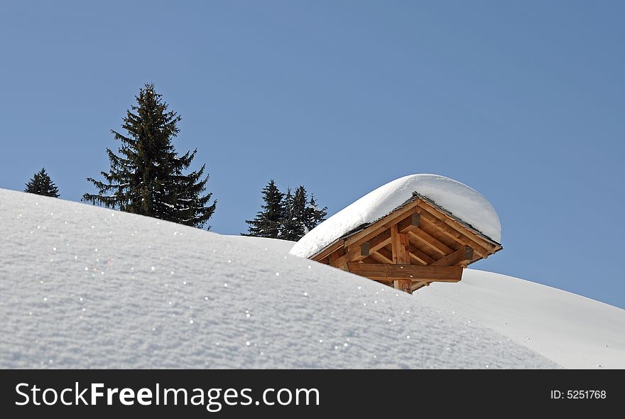 Winter scenery with snow covered slope, trees and blue sky