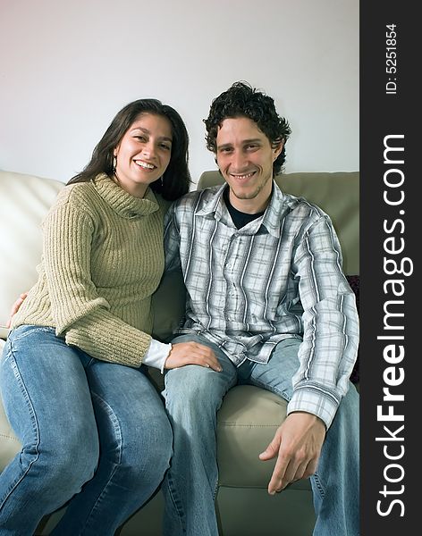 Attractive couple hugging each other and smiling while sitting on their living room couch. Attractive couple hugging each other and smiling while sitting on their living room couch