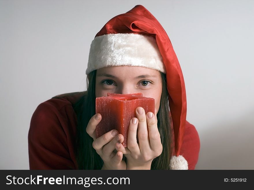 Horizontally framed shot of an attractive woman in a santa hat looking seductively at the camera over a red candle. Horizontally framed shot of an attractive woman in a santa hat looking seductively at the camera over a red candle