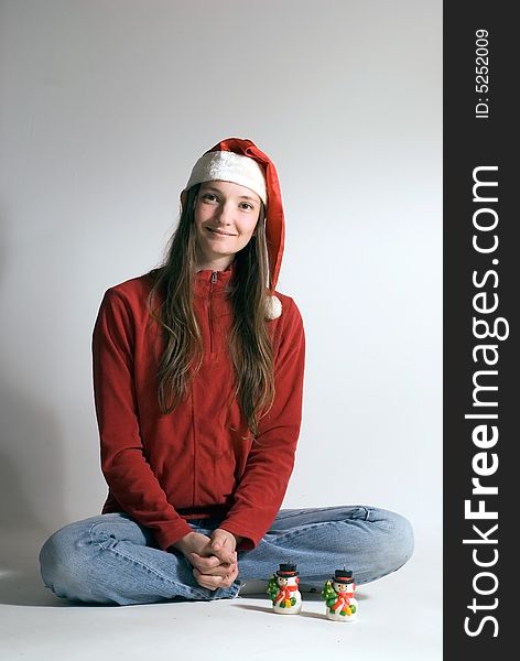 Beautiful young woman in a red jacket, jeans and a santa hat with two snowman ornaments in front of her. Vertically framed shot. Beautiful young woman in a red jacket, jeans and a santa hat with two snowman ornaments in front of her. Vertically framed shot.