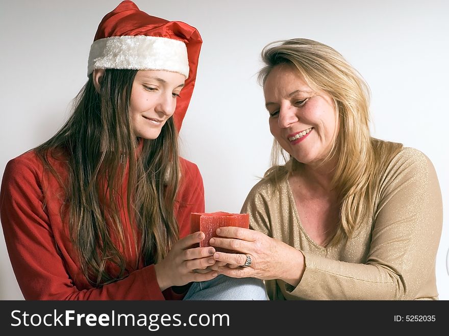 Mature woman and her daughter getting into the christmas spirit and holding a burning christmas candle. Both women are looking at the candle. Mature woman and her daughter getting into the christmas spirit and holding a burning christmas candle. Both women are looking at the candle