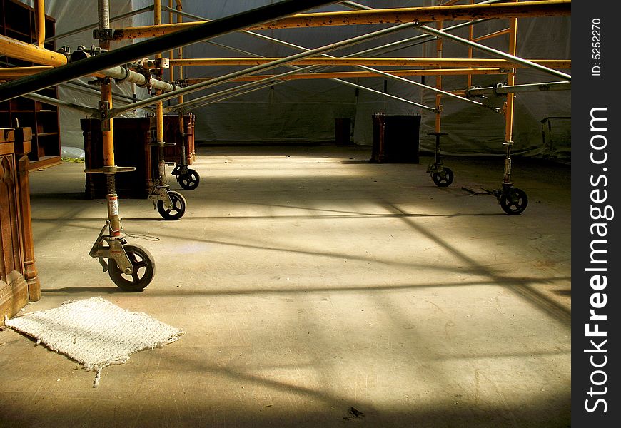 Horizontal shot of a lower half of a scaffolding in a room under construction.  Beautiful yellow sunlight is pouring into the room from above. Horizontal shot of a lower half of a scaffolding in a room under construction.  Beautiful yellow sunlight is pouring into the room from above.