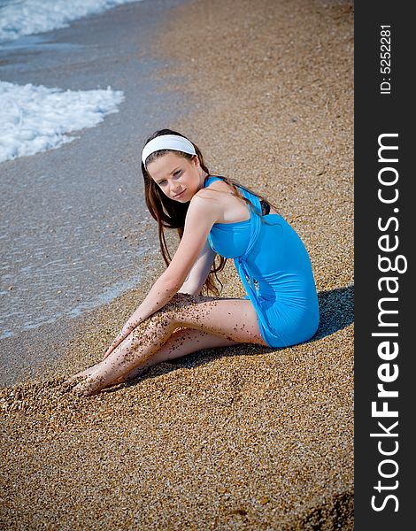 Beuatiful girl wearing blue dress sitting on sand at beach near sea water. Beuatiful girl wearing blue dress sitting on sand at beach near sea water