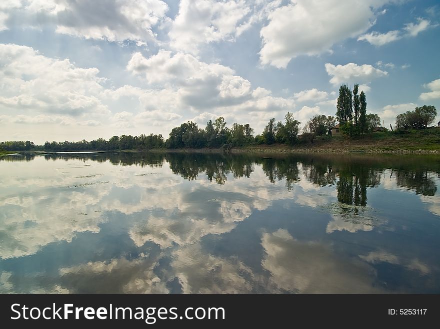 Cloudy sky with forest and reflection in river