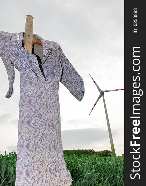 Scarecrow on a corn field with modern windmill. Scarecrow on a corn field with modern windmill