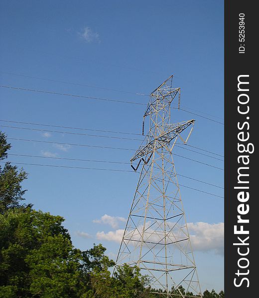 Power Transmission Tower is set against a blue sky framed by nearby trees with a cloud in the background.