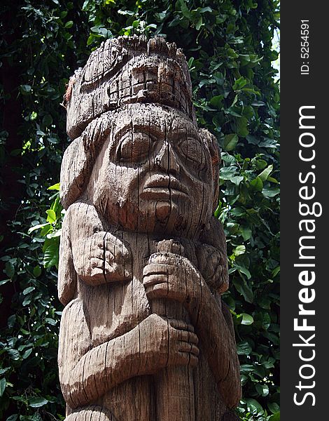 A hand-carved totem pole with faces on it wears in the weather.