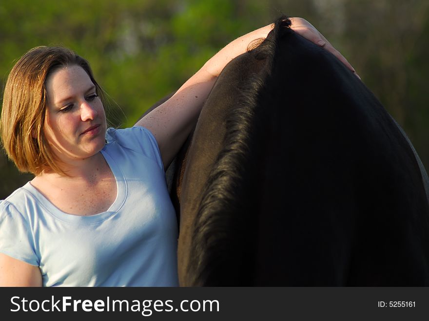 Woman with arm on the back of black horse. Woman with arm on the back of black horse