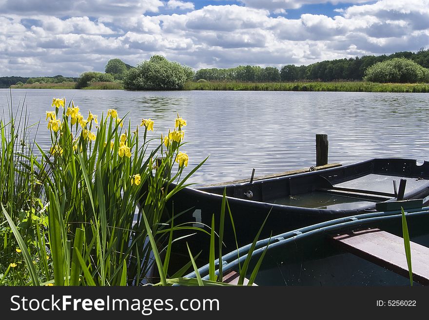 Two old boats at the edge of a lake, with one boat almost sunk. Two old boats at the edge of a lake, with one boat almost sunk