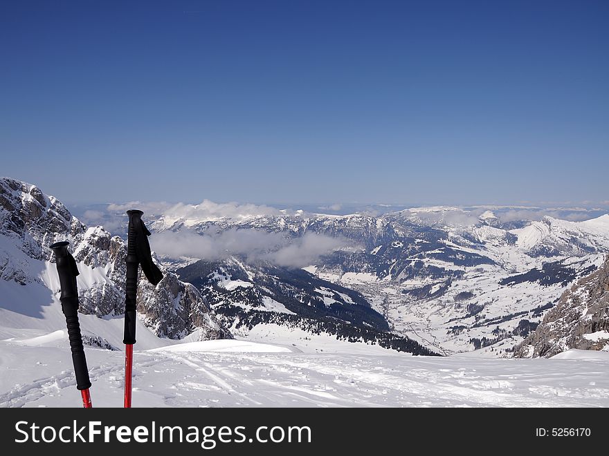 Winter moutain scene with skisticks and view of a valley. Winter moutain scene with skisticks and view of a valley