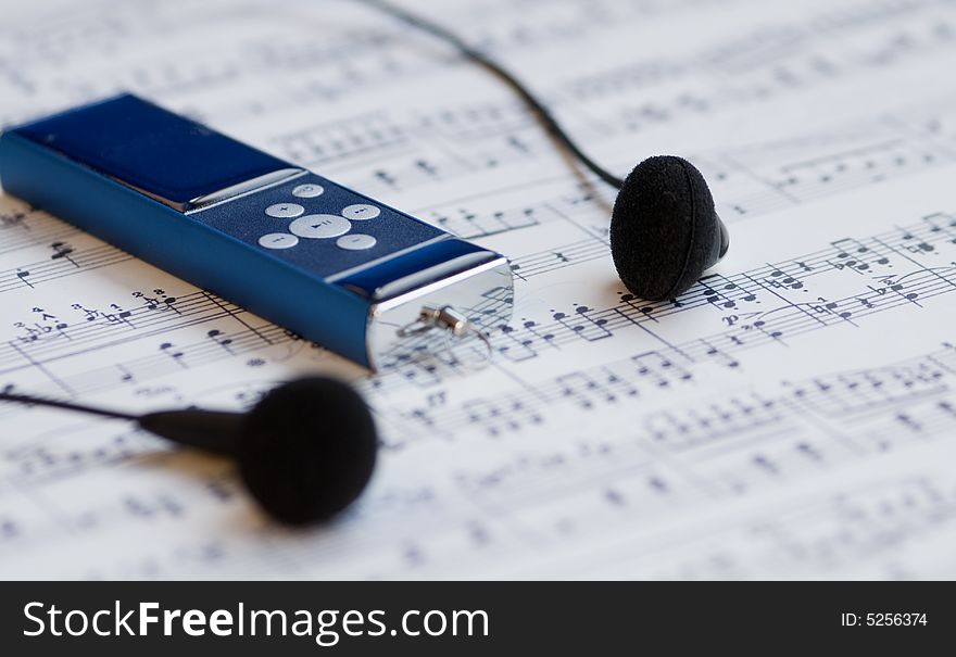 Mp3 player and earphones on a music sheet background