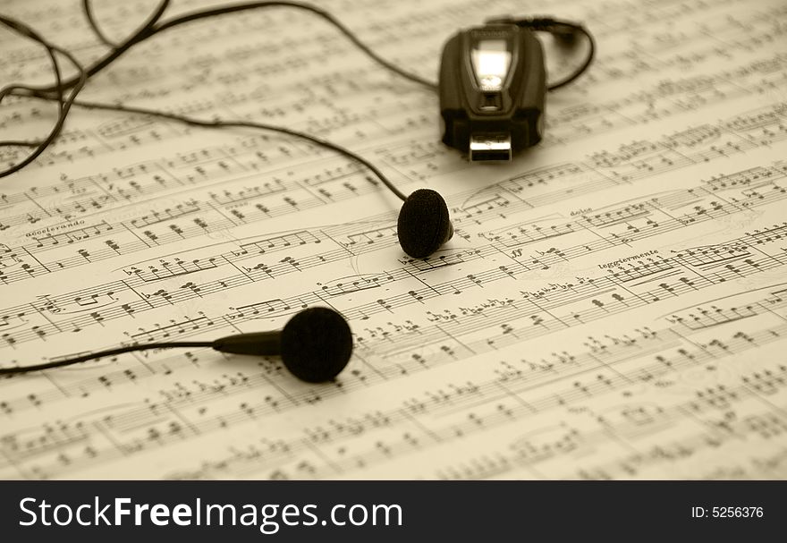 Mp3 player and earphones on a music sheet background