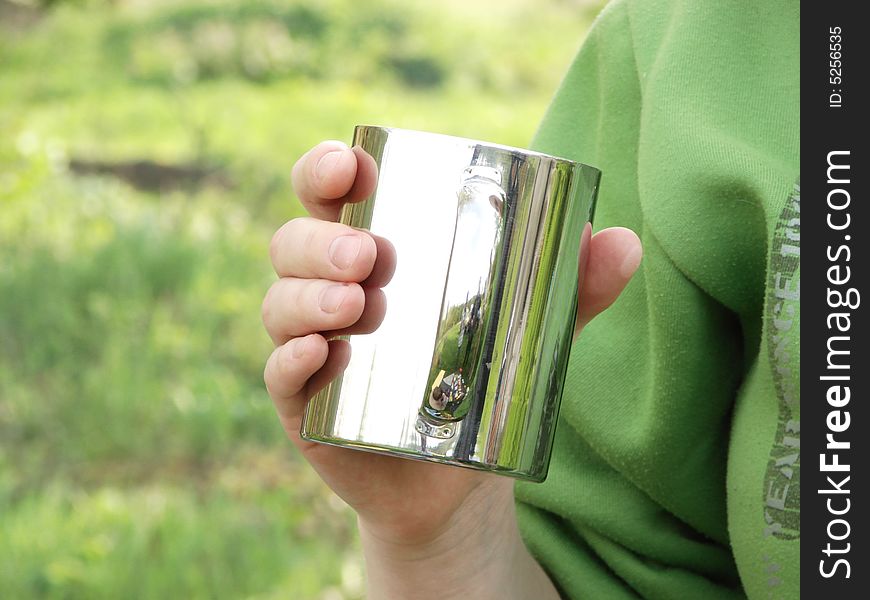 Girl holds silver metal cup in hand and drinks. Girl holds silver metal cup in hand and drinks