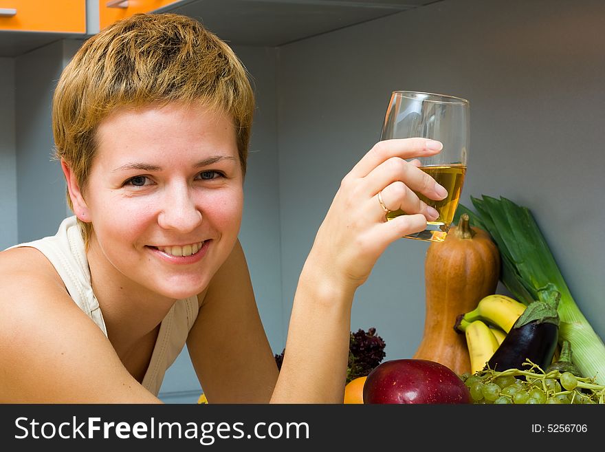 Beautiful woman with glass of juice and fresh fruits in the kitchen