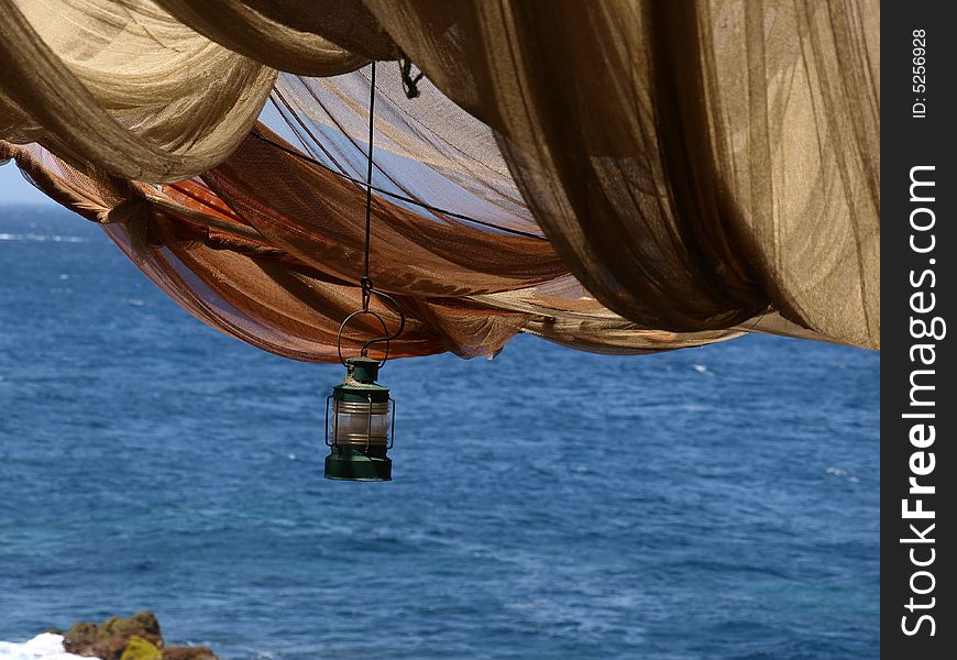 Storm lamp hanging below fishing net canopy. Storm lamp hanging below fishing net canopy