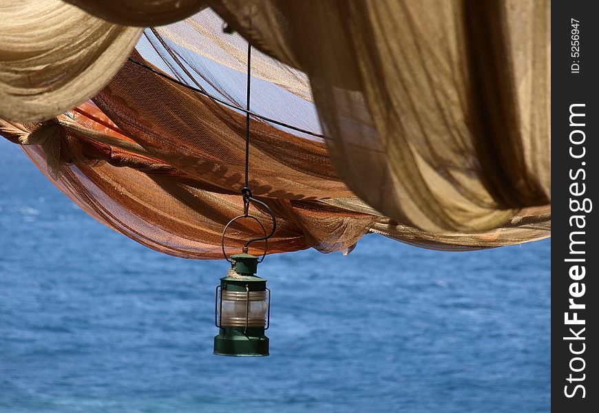 Single gas lamp hanging below fishing net canopy. Single gas lamp hanging below fishing net canopy