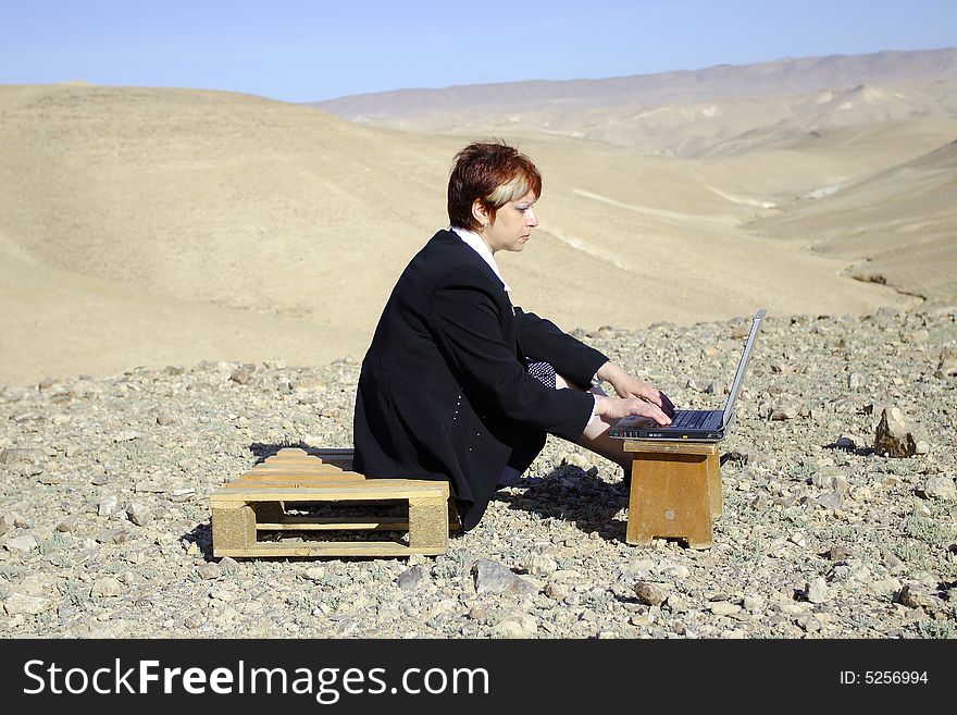 Young woman working with laptop in Judean desert. Young woman working with laptop in Judean desert