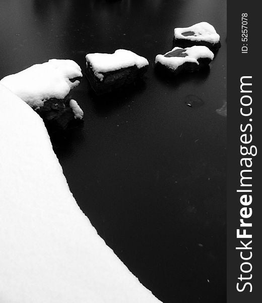 Stones in a pool covered with snow