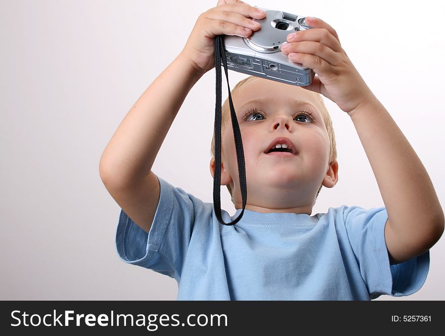 Shy toddler holding a silver camera, looking at his object. Shy toddler holding a silver camera, looking at his object
