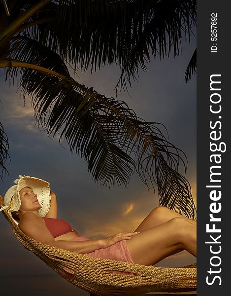 View of a woman lounging in hammock after sunset. View of a woman lounging in hammock after sunset