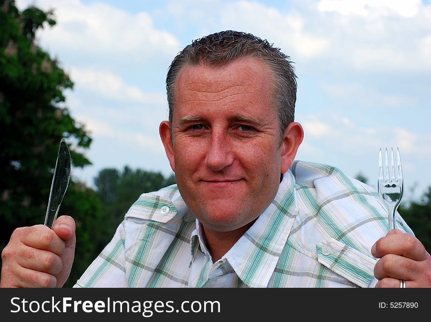 Shot of a man with his picnic cutlery ready to eat. Shot of a man with his picnic cutlery ready to eat