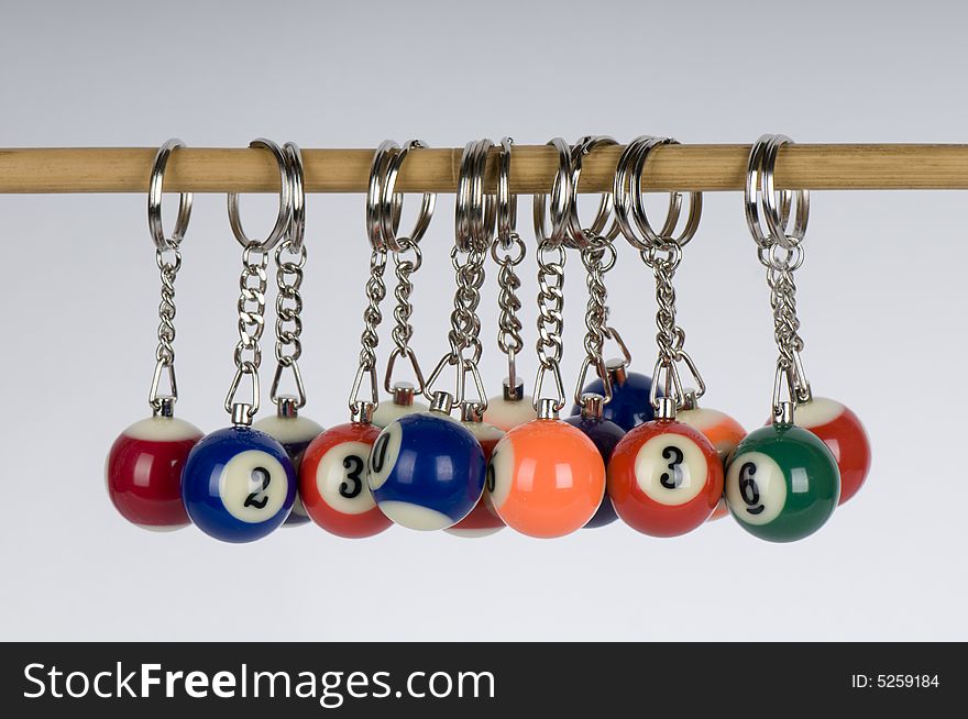 A number of pool balls miniaturized and attached to keyrings and hanging off a stick. A number of pool balls miniaturized and attached to keyrings and hanging off a stick.